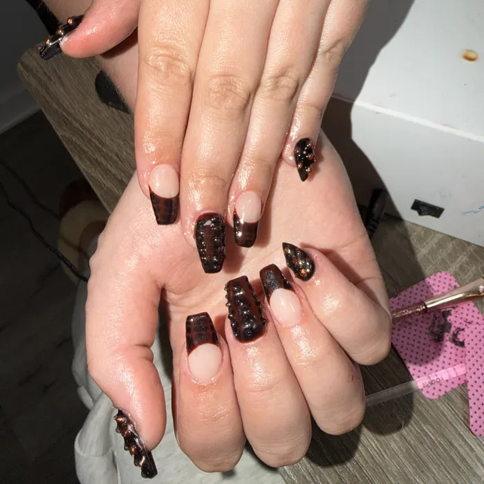 Black and amber jelly French tips with 3D metal stud accents on coffin nails