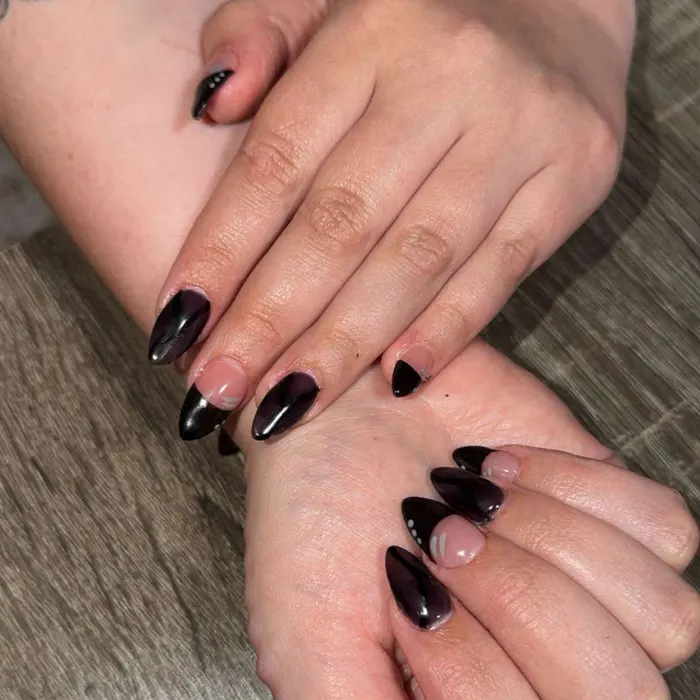 Glossy black almond nails with a cat-eye chrome shimmer, plus French tips and tiny dot details